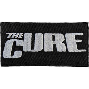 Könnte beinhalten: Ein rechteckiger, schwarz bestickter Aufnäher mit dem Schriftzug THE CURE in fetten, weißen Großbuchstaben. Das Design ist mit einem dichten Fadenmuster auf einem einfarbigen schwarzen Stoffhintergrund gestickt, was ein klares Bild erzeugt.