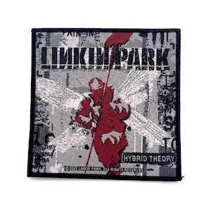 Puede incluir: Un parche bordado cuadrado que presenta el logotipo de Linkin Park en texto negro en la parte superior y las palabras Hybrid Theory en un recuadro rectangular en la parte inferior. Una figura alada roja central sobre un fondo gris y negro.