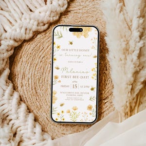 May include: A digital invitation for a first birthday party with a bee theme. The invitation is on a white background with yellow flowers, bees, and honeycomb. The text reads "Our little honey is turning one!" and "Join us for a Melania's First Bee-Day!" The date and time of the party are listed as "Friday, 15 at 2 PM". The location is "Space Drive 3145, Denver, Florida, 11097".