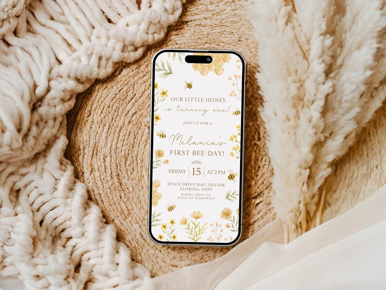 May include: A digital invitation for a first birthday party with a bee theme. The invitation is on a white background with yellow flowers, bees, and honeycomb. The text reads "Our little honey is turning one!" and "Join us for a Melania's First Bee-Day!" The date and time of the party are listed as "Friday, 15 at 2 PM". The location is "Space Drive 3145, Denver, Florida, 11097".