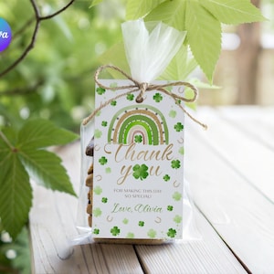 May include: A clear cellophane bag tied with twine, containing cookies and a gift tag. The tag features a green and gold rainbow design, shamrocks, and the words "Thank you" in gold script. The tag also includes the text "For making this day so special! Love, Olivia."