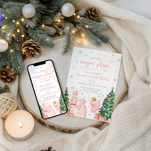 Könnte beinhalten: Ein Smartphone und eine Einladungskarte mit einem Aquarelldesign für eine Geburtstagsfeier. Auf der Einladung steht "Our Little Sugar Plum is Turning One" mit dem Namen "Amanda" und dem Datum "10". Das Design umfasst Nussknacker, Ballerinas und Weihnachtsbäume.