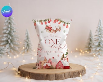 May include: A white gift bag with a Christmas theme. The bag features illustrations of Santa Claus in a sleigh, houses, snowflakes, and the text "It's the most ONE derful TIME OF THE YEAR."