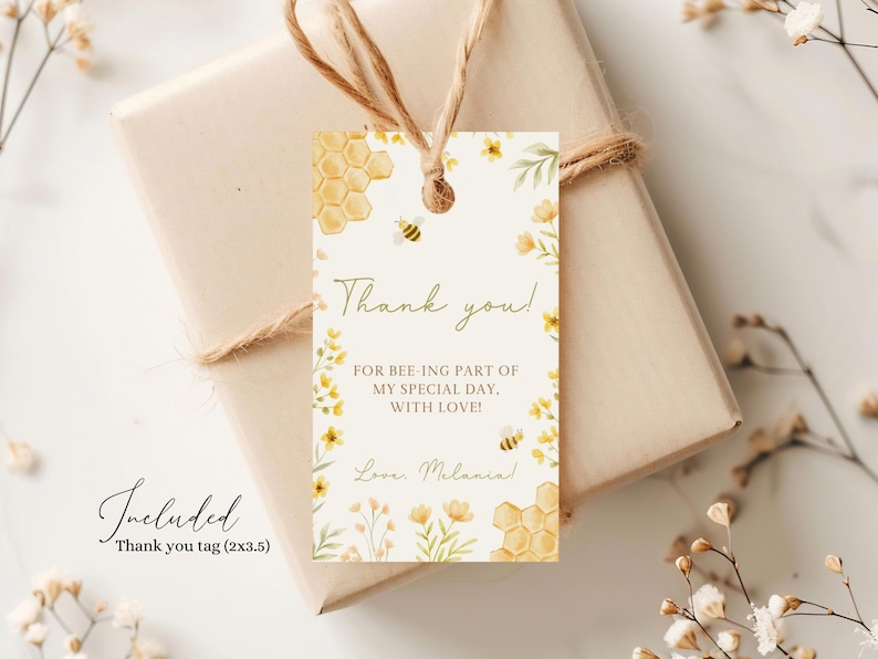 May include: A thank you tag with a bee and honeycomb design. The tag is white with yellow flowers and green leaves. The text on the tag reads "Thank you! For bee-ing part of my special day. With love! Love, Melanin".