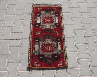 May include: A red, green, and white patterned runner rug with a fringed edge. The rug has a traditional design with geometric shapes and floral motifs.