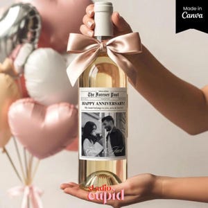 May include: A clear wine bottle with a white cap and a peach-colored bow. The label reads "The Forever Post HAPPY ANNIVERSARY!" with a black and white photo of a couple. The bottle is held in front of a background of balloons.