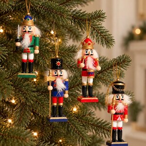 Könnte beinhalten: Vier hängende Nussknacker-Ornamente mit bemalten Holzfiguren in traditionellen Uniformen. Jeder Soldat trägt eine Krone oder einen Hut, hat einen weißen Bart und hält ein kleines Zubehörteil, aufgehängt an goldenen Schnüren.