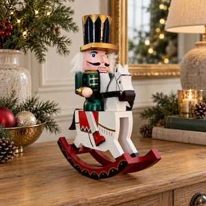 May include: A wooden nutcracker figure wearing a black top hat with gold trim, a green jacket, and white hair, mounted on a white rocking horse with red rockers. The nutcracker has a painted face with a mustache and is positioned in profile.