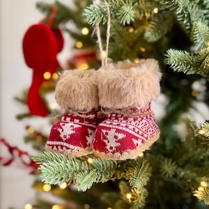 Puede incluir: Un par de adornos navideños de punto rojo y blanco en forma de bota con ribete de piel sintética. Las botas están decoradas con un patrón de copo de nieve blanco y cuelgan de un árbol de Navidad. Las botas miden aproximadamente 7.6 cm de largo.