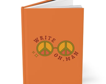 以下が含まれることがあります： オレンジ色のノートブックに、茶色の文字で「WRITE ON, MAN」と書いてあり、緑、オレンジ、赤の平和マークのグラフィックが描かれています。