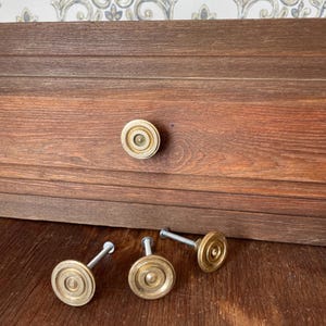 Può includere: Una tazza di ceramica bianca con manico nero e la scritta "But First, Coffee" in nero, in grassetto. La tazza è appoggiata su una superficie bianca. La tazza è alta circa 10 cm.