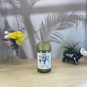 May include: A green glass bottle with a white label that reads 