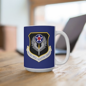 May include: White ceramic mug featuring the Air Force Special Operations Command emblem. The emblem is set against a navy blue background and includes a star, wings, and a sword. The text "AIR FORCE SPECIAL OPERATIONS COMMAND" is displayed.