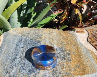 May include: A round, blue and gold resin bottle stopper. The stopper has a swirl pattern and a shiny finish.