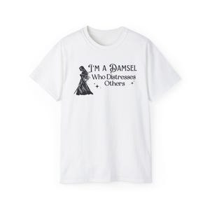 May include: White t-shirt with a black silhouette of a woman holding a sword and the text "I'm a Damsel Who Distresses Others".