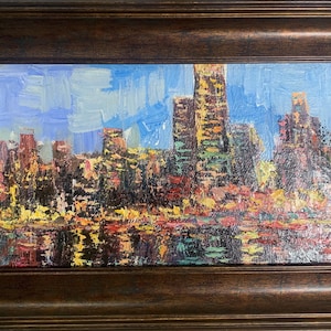 May include: An oil painting of a city skyline at dusk, featuring thick, textured brushstrokes in shades of blue, yellow, orange, and dark brown. The scene depicts buildings reflected in water, all enclosed within a dark, ornate wooden frame.