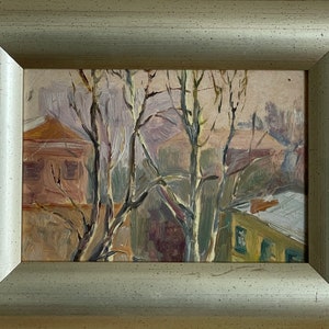 Puede incluir: Una pintura al óleo enmarcada que representa una escena rural con dos casas y árboles en primer plano. Las casas están pintadas en tonos marrones y verdes, y los árboles son de un marrón claro con troncos blancos. El fondo es de un gris suave y apagado.