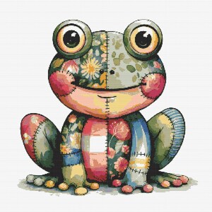 Op de afbeelding: Een patchwork kikker met een glimlachend gezicht, gemaakt van verschillende stoffen met bloemenpatronen, blauw, groen, roze en wit.