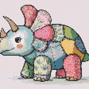 May include: A cross-stitch depiction of a friendly triceratops dinosaur. The dinosaur is light blue with patches of various floral patterns in pink, green, and yellow. It has a smiling face and a light pink background.