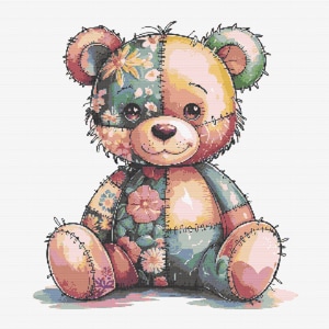 Op de afbeelding: Een patchwork teddybeer met bloemenpatronen in roze, groene en gele tinten. De beer zit met gekruiste benen en heeft een lieve uitdrukking op zijn gezicht.