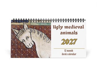 May include: A spiral-bound desk calendar titled Ugly medieval animals 2027 12 month desk calendar. The cover features a white horse illustration against a dark red patterned background with a white side panel containing the black and gold text.