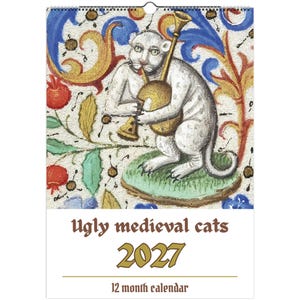 Może przedstawiać: Kalendarz 12-miesięczny na rok 2027 pod tytułem Ugly medieval cats. Okładka przedstawia średniowieczną ilustrację białego kota grającego na złotym instrumencie dętym, na tle dekoracyjnego wzoru z czerwonymi granatami oraz niebieskimi liśćmi.