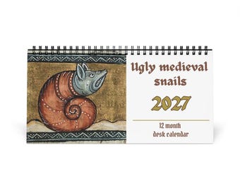 May include: A 2027 desk calendar with a black spiral binding. The left side features a medieval-style illustration of a snail with a grey head and a brown shell on a gold background. The right side displays the text Ugly medieval snails 2027.
