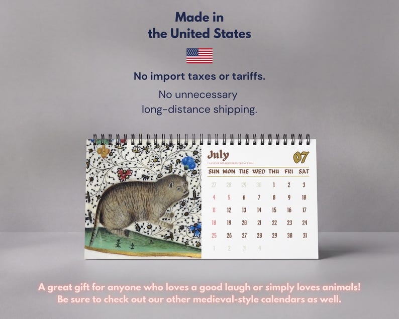 May include: A spiral-bound desk calendar featuring a medieval-style illustration of a cat on the left page and the month of July with a grid of dates on the right. The text includes the month name July, the number 07, and days of the week.