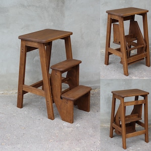 Puede incluir: Un taburete de madera con dos peldaños. El taburete está hecho de madera marrón oscura y tiene un diseño sencillo. Es una herramienta útil para alcanzar lugares altos.