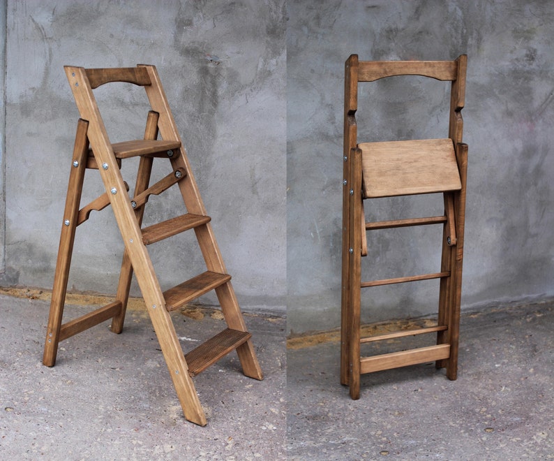 K&ouml;nnte beinhalten: Zwei Holzstufenhocker, einer zusammengeklappt und einer ausgeklappt. Beide Hocker haben eine braune Beize und sind aus massivem Holz gefertigt. Der ausgeklappte Hocker hat vier Stufen und eine obere Plattform.