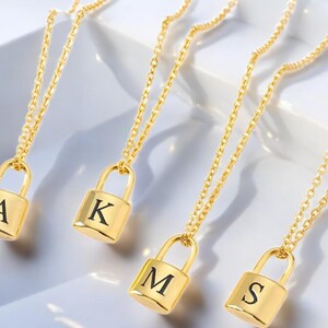 May include: Four gold necklaces with padlock pendants, each engraved with a different letter: A, K, M, and S.