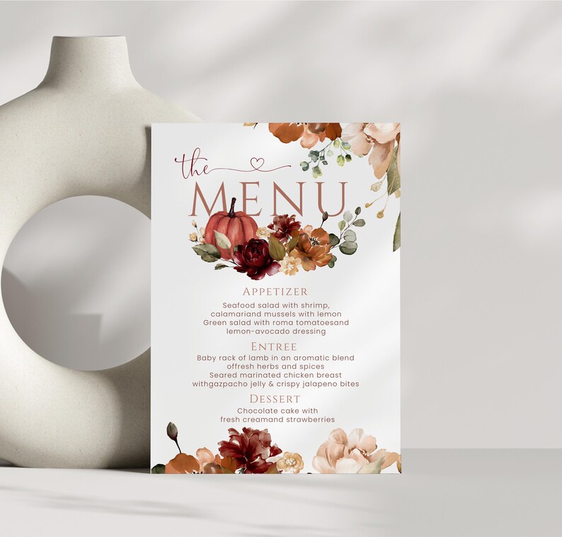 以下が含まれることがあります： 「the MENU」という文字がスクリプト体とセリフ体で記された長方形のメニューカード。カボチャ、濃い赤のバラ、オレンジ色の花の透明水彩画が描かれています。メニューには前菜、メインディッシュ、デザートの項目が記載されています。
