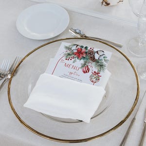 May include: A rectangular paper menu card featuring a watercolor illustration of pine branches, red poinsettias, pinecones, and striped ornaments. The text reads The MENU appetizer Seafood salad with shrimp, calamari and mussels with lime.