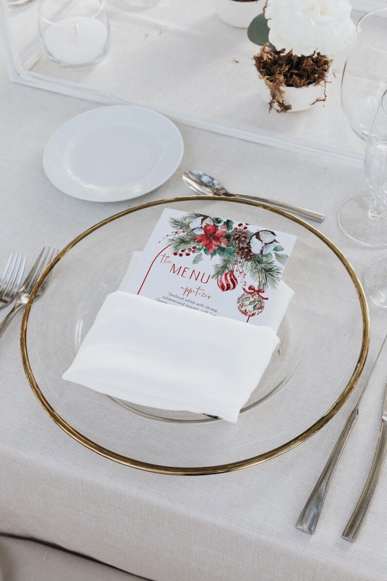May include: A rectangular paper menu card featuring a watercolor illustration of pine branches, red poinsettias, pinecones, and striped ornaments. The text reads The MENU appetizer Seafood salad with shrimp, calamari and mussels with lime.