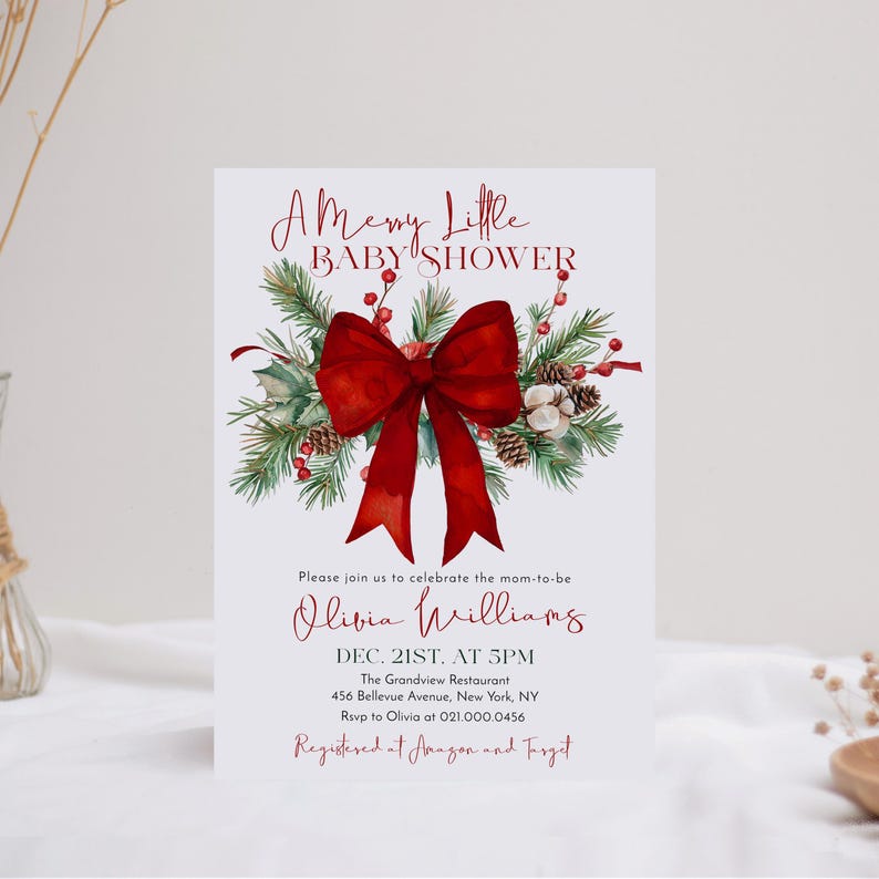 Peut inclure: Une carte d'invitation rectangulaire blanche pour une f&ecirc;te pr&eacute;natale avec un grand n&oelig;ud rouge, des branches de pin vertes, des pommes de pin et des baies rouges. Le texte indique A Merry Little BABY SHOWER, Olivia Williams, Dec. 21st. at 5pm, The Grandview Restaurant, 456 Bellevue Avenue, New York, NY, Rsvp to Olivia at 021.000.0456, Registered at Amazon and Target.
