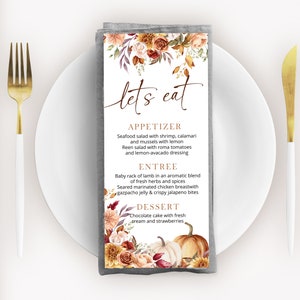 May include: A gray linen napkin with a fall-themed menu printed on it. The menu features a floral design with pumpkins and the text "let's eat". The menu includes appetizers, entrees, and desserts.