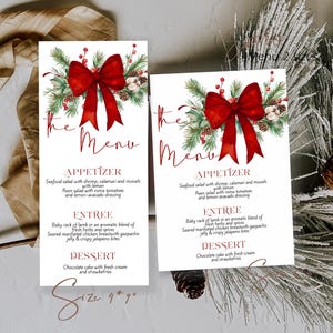 May include: Two white menu cards with a festive design. Each card features a red bow, greenery, and text that reads "The Menu." The menu includes appetizer, entree, and dessert options. The size is 9" x 7".
