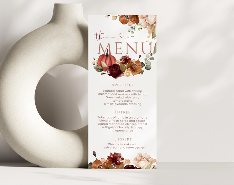 以下が含まれることがあります： 「the MENU」という文字と、カボチャ、濃い赤とオレンジの花、緑の葉の水彩画が描かれた縦型のメニューカード。メニューにはAppetizer、Entree、Dessertのセクションと料理の説明が記載されています。