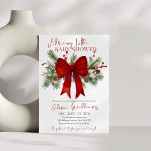 Peut inclure: Une carte d'invitation pour baby shower blanche avec un grand n&oelig;ud rouge, des branches de pin vertes, des baies rouges et des pommes de pin. Le texte indique A Merry Little BABY SHOWER, Olivia Williams, Dec. 21st at 5pm, The Grandview Restaurant.