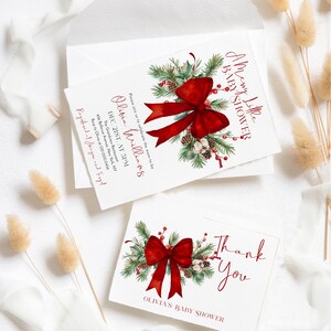 Peut inclure: Un ensemble de faire-part de baby shower et de carte de remerciement blanc avec une illustration aquarelle d'un grand n&oelig;ud rouge, de branches de pin vertes, de pommes de pin et de baies rouges. Le texte indique A Merry Little Baby Shower.