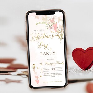 Könnte beinhalten: Ein Smartphone zeigt eine Einladung zu einer Valentinstagsparty. Die Einladung hat ein Blumendesign mit rosa Herzen und goldenem Text, der "Valentine's Day Party" lautet. Die Veranstaltung wird von der Familie Paterson am 14. Februar um 20 Uhr veranstaltet.