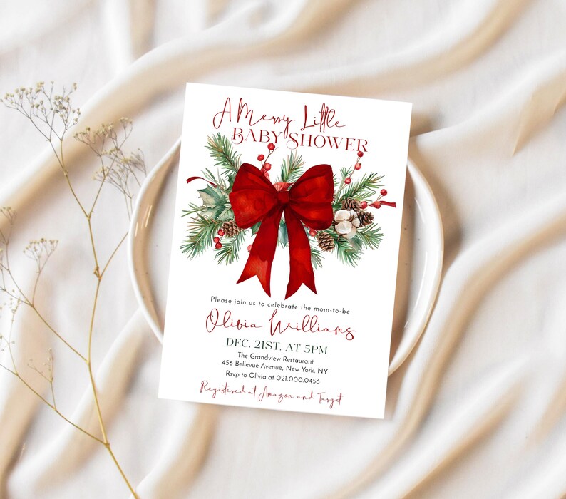 Peut inclure: Une carte d'invitation rectangulaire blanche pour une f&ecirc;te pr&eacute;natale avec un grand n&oelig;ud rouge, des branches de pin vertes, des pommes de pin et des baies rouges. Le texte indique A Merry Little BABY SHOWER, Olivia Williams, Dec. 21st, at 5pm.