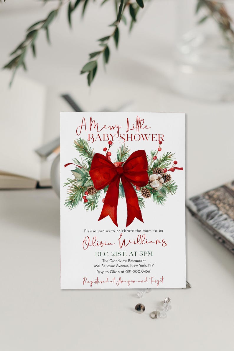 Peut inclure: Une carte d'invitation blanche pour une baby shower orn&eacute;e d'un grand n&oelig;ud rouge, de branches de pin, de pommes de pin et de baies rouges. Le texte indique A Merry Little BABY SHOWER, Olivia Williams, Dec. 21st at 5pm, The Grandview Restaurant.