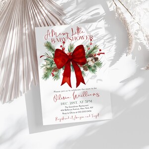 Peut inclure: Une carte d'invitation blanche pour une baby shower avec un grand n&oelig;ud rouge, des branches de pin vertes, des baies rouges et des pommes de pin. Le texte indique A Merry Little BABY SHOWER, Olivia Williams, Dec. 21st, at 5pm, The Grandview Restaurant.