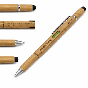 May include: A bamboo multi-tool pen featuring a silver metal clip, a built-in spirit level, and a ruler printed on the barrel. The pen is engraved with the text "I love you Daddy" and "Sarah". It includes a stylus tip and a ballpoint pen nib.