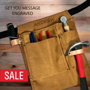 May include: A brown leather tool apron with multiple pockets, a hammer, pliers, and a roller. The apron has a black belt and the name "ANDREW" is engraved on the front.