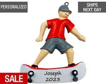 May include: A red and white personalized Christmas ornament featuring a boy on a skateboard. The ornament is decorated with the name "Joseph" and the year "2023".