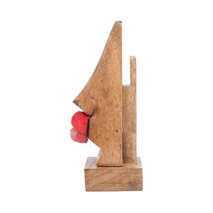 May include: Wooden sculpture of a face with red lips. The sculpture is made of light brown wood and is standing on a wooden base.