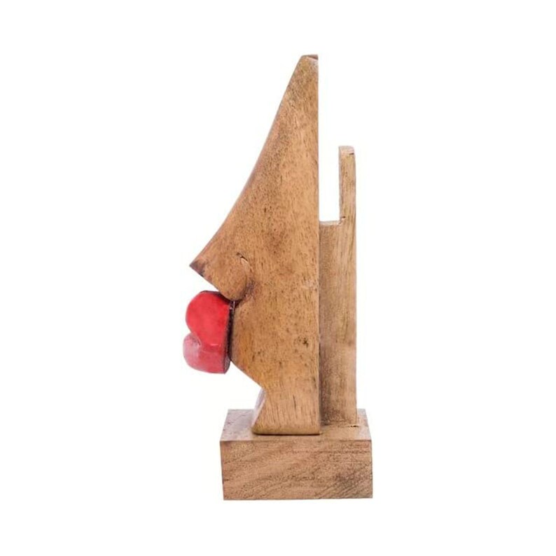 May include: Wooden sculpture of a face with red lips. The sculpture is made of light brown wood and is standing on a wooden base.