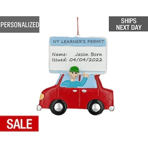 May include: Red car Christmas ornament with a driver and a sign that reads "NY LEARNER'S PERMIT" with the name "Jason Born" and the date "04/04/2022".